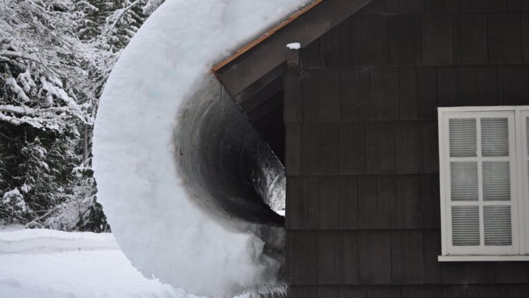 Une accumulation de neige et de glace au bord d’un toit.